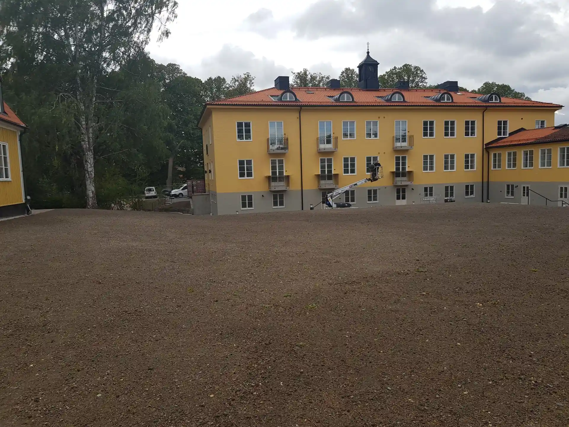 Gulmålad byggnad med skylift och nyanlagd grusplan